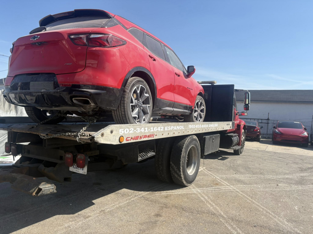 A red SUV loaded onto a flatbed tow truck for transport by Tow & go in Louisville, KY.