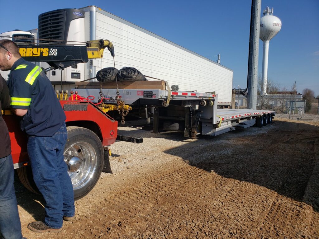 A red tow truck from Terry's Auto Service and Towing, LLC, moving a large flatbed trailer in Springfield, MO.