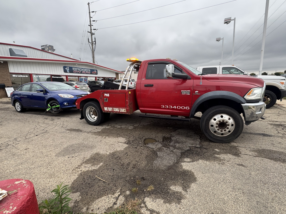 A red PNB towing truck actively towing a blue sedan from a parking lot in Madison, WI.