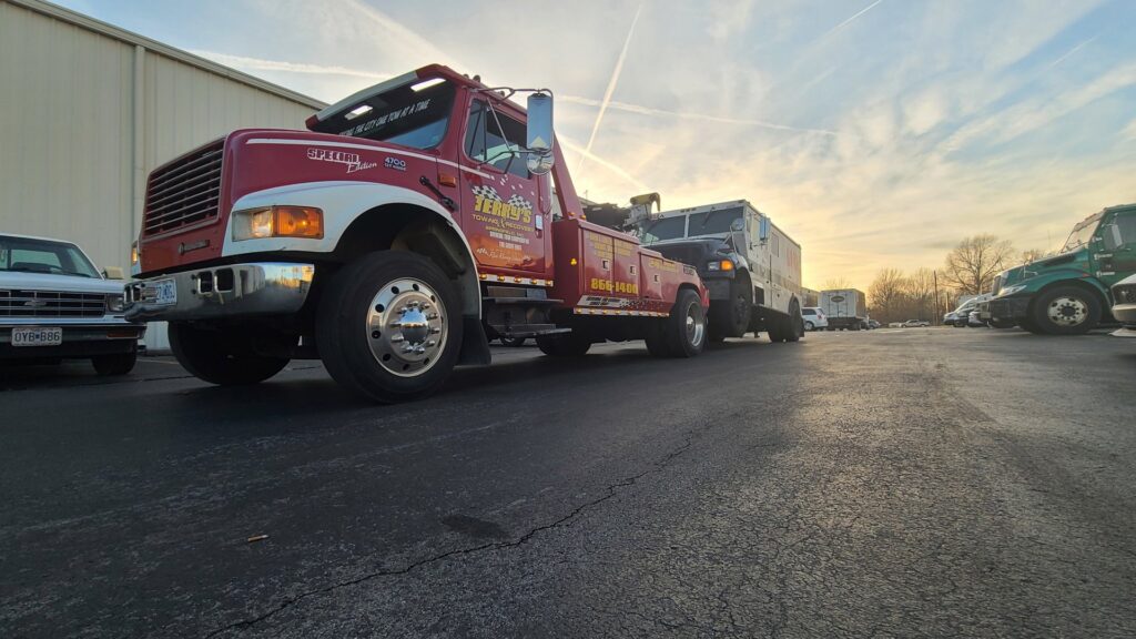 A red tow truck from Terry's Auto Service and Towing, LLC, towing a large white box truck in Springfield, MO.