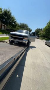 A red tow truck towing a large white travel trailer for RDZ Towing Service 24/7 in Dallas, TX.
