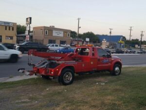 A red wrecker truck from Alanis Wrecker Service parked roadside in San Antonio, TX.