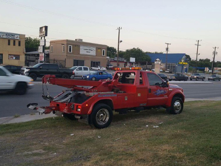 A red wrecker truck from Alanis Wrecker Service parked roadside in San Antonio, TX.