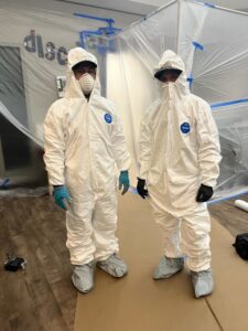 Two Rainbow Restoration of Meridian remediation specialists in Tyvek suits and respirators working on a water-damaged site in Meridian, ID.