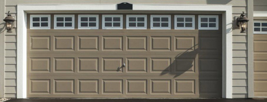 A residential beige garage door with a row of windows across the top, installed by Doors & more,inc in Quincy, IL