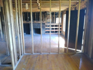 Residential interior stripped to studs with a visible fireplace, showcasing demolition work by Building Assisting Group Demolition INC in Tacoma, WA.