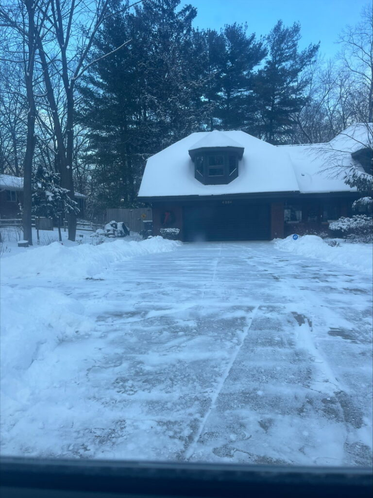 A residential driveway partially cleared of snow by Snow Scholars - Snow Removal By College Students in Madison, WI.