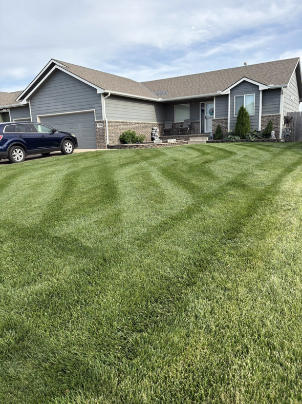 Residential front lawn with neatly mowed grass and curved stripes by EZ Cut Lawn Care & Landscaping, Crestview, FL.