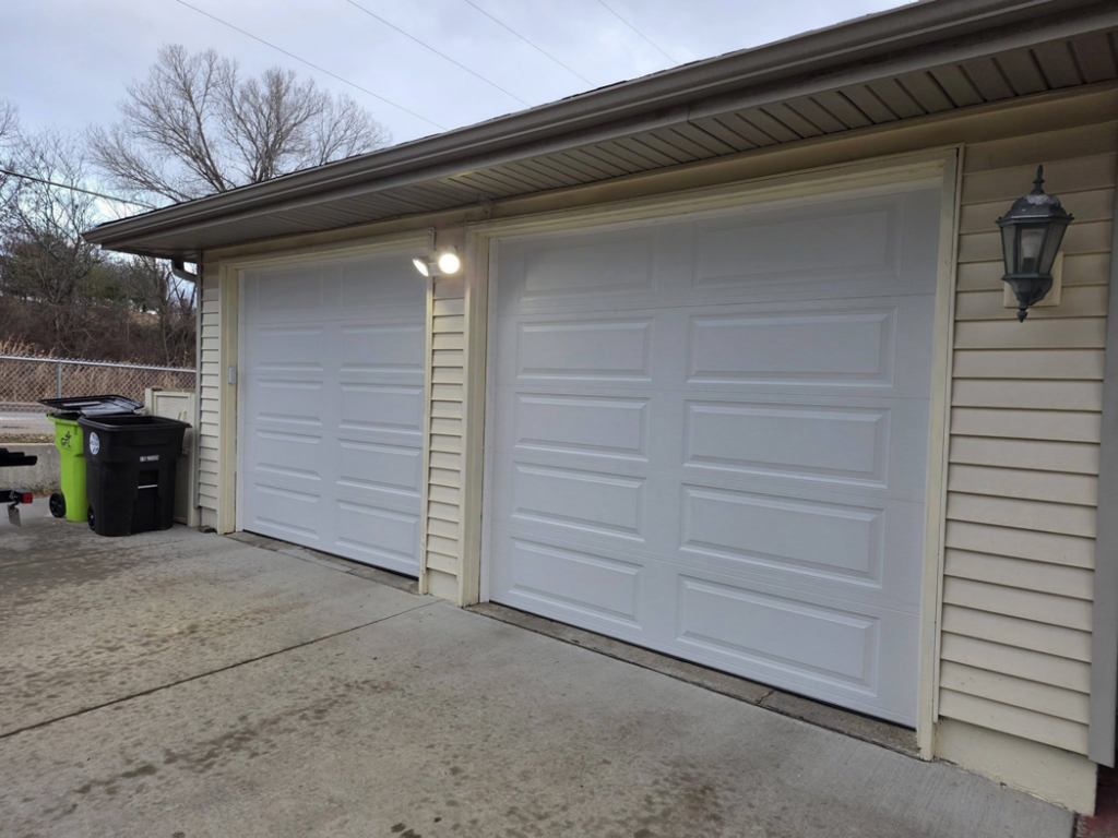 Two newly installed white panel garage doors on a residential home by American Standard Garage Doors in Independence, MO.