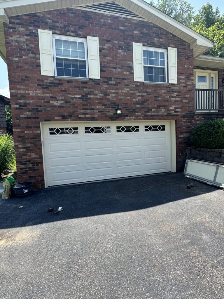 A new white residential garage door with decorative windows installed on a brick house by 4thgenerationsdoors in Huntington, WV.