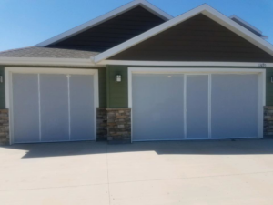 Two light-colored garage screen doors installed on a residential home by McCody Overhead Doors in Williston, ND