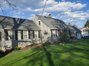 A residential house showcasing new gray siding and a dark roof completed by Trabajo en roofing y siding in Lowell, MA.