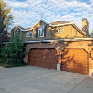 A residential house featuring two attractive wooden-style garage doors installed by Canyon Overhead Doors in Salt Lake City, UT.
