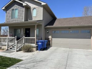 A residential house featuring a newly installed beige garage door by Barrett Overhead Doors in Idaho Falls, ID.