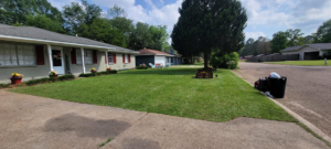 A residential lawn with a mower and equipment, showcasing a recently completed lawn care job by Caffey's Lawn Care LLC in Jackson, MS.