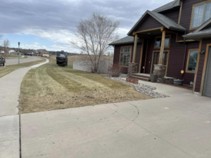A residential front yard showcasing fresh mowing stripes from Top Cut Lawn Care and Snow Removal services in Minot, ND.