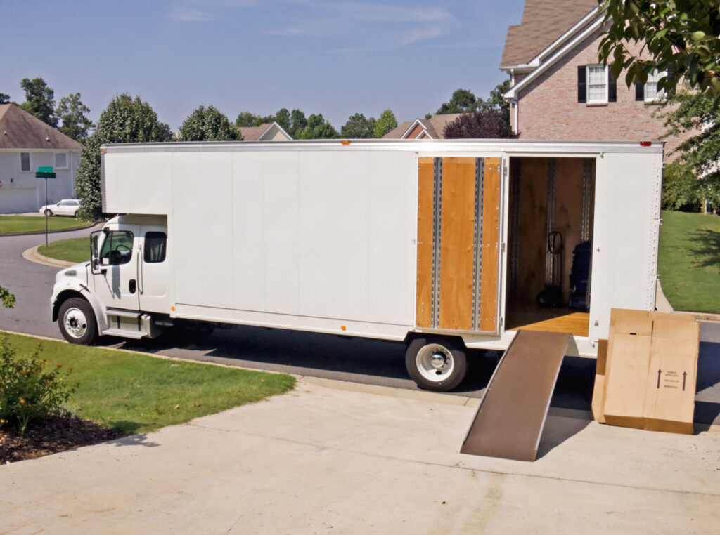 A large white moving truck with its ramp down, parked in a residential driveway for a move by E.L.I Movers LLC in Houston, TX.