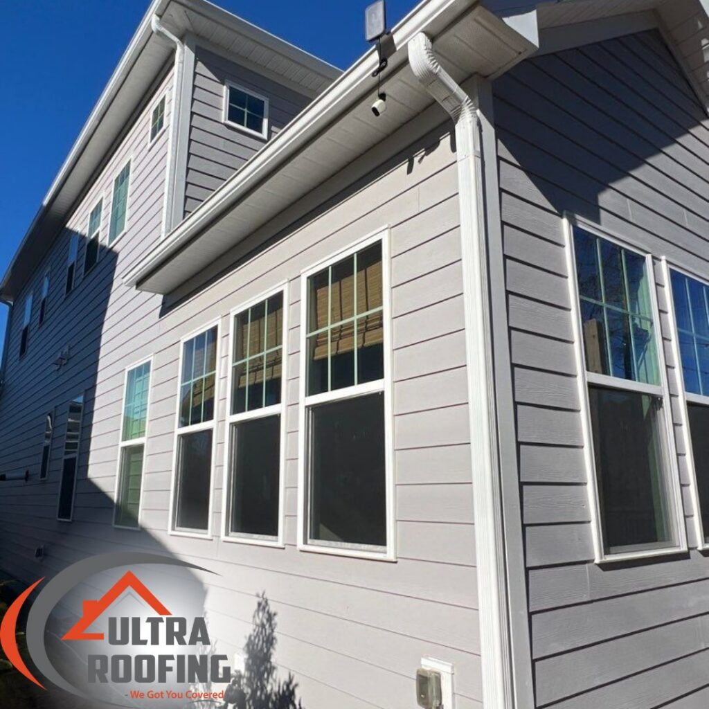The side of a house with recently replaced light gray siding by Ultra Roofing in Cary, NC