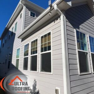 The side of a house with recently replaced light gray siding by Ultra Roofing in Cary, NC