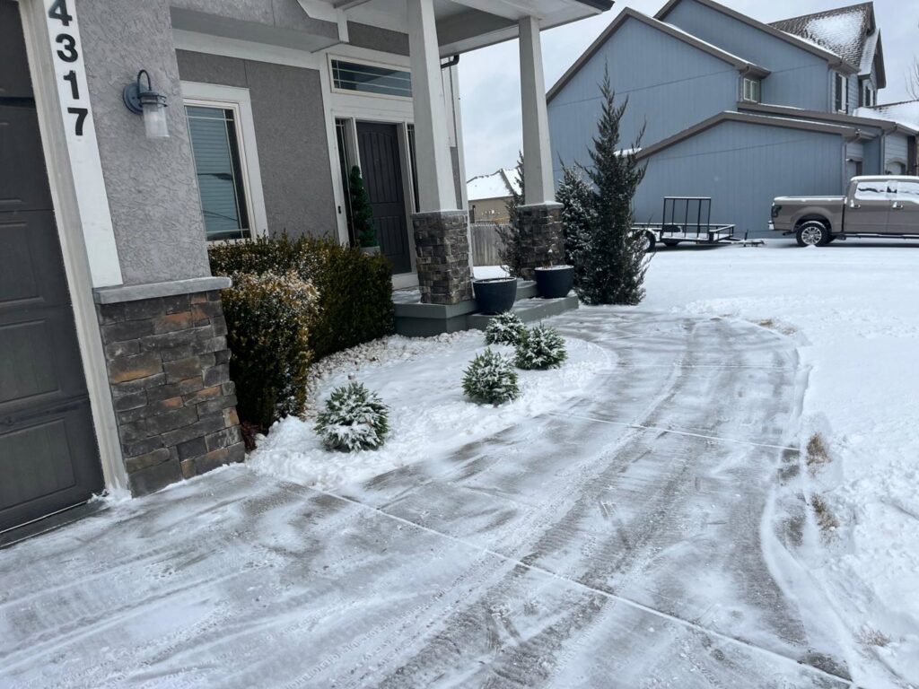 Professional residential snow removal service on a driveway and walkway by Eco Verde Landscaping and Snow Removal LLC in Independence, MO.