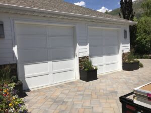 Residential home with newly installed white panel garage doors by Up N Over Garage Doors LLC in Layton, UT.