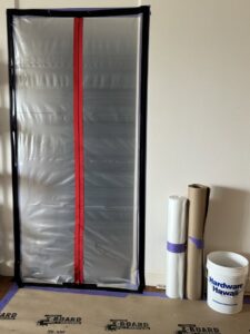 Plastic sheeting covering a doorway with restoration materials on the floor, indicating a job setup by Island Restoration LLC in Kapolei, HI.