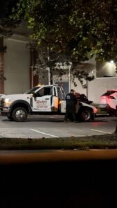 A Ricky's Towing & Recovery LLC tow truck with an operator working to secure a car for towing at night in Derwood, MD.