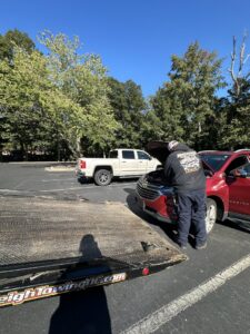 A Raleigh Towing & Recovery technician providing roadside assistance to a red SUV in Raleigh, NC.