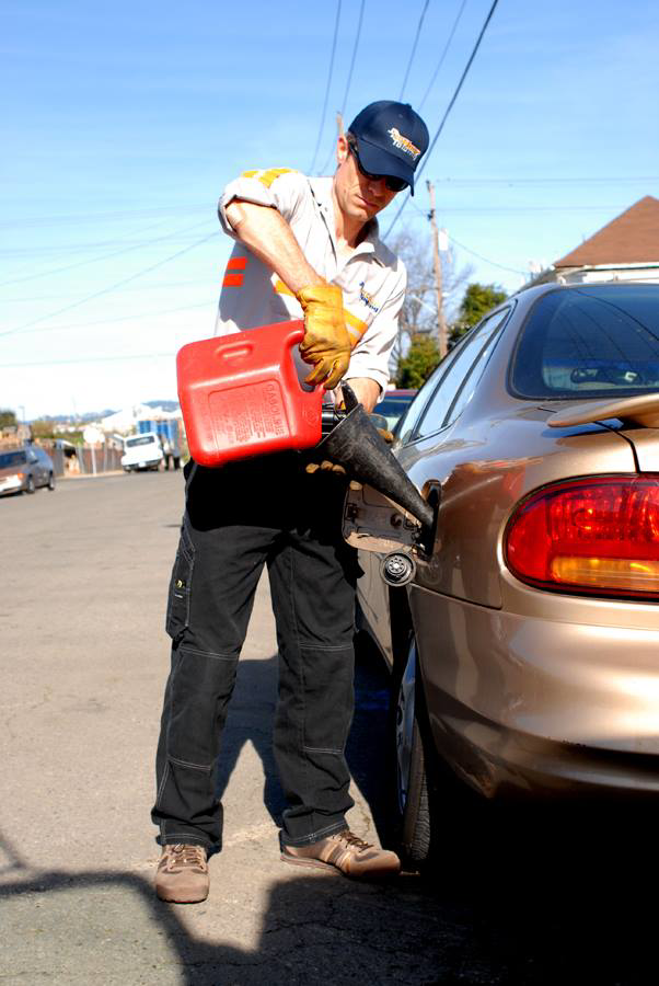 A service technician pouring gasoline into a car for roadside fuel delivery from Emergency Towing Sacramento, CA.