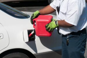 A service professional delivering gasoline to a stranded vehicle on the roadside, a service offered by Emergency Towing Sacramento, CA.
