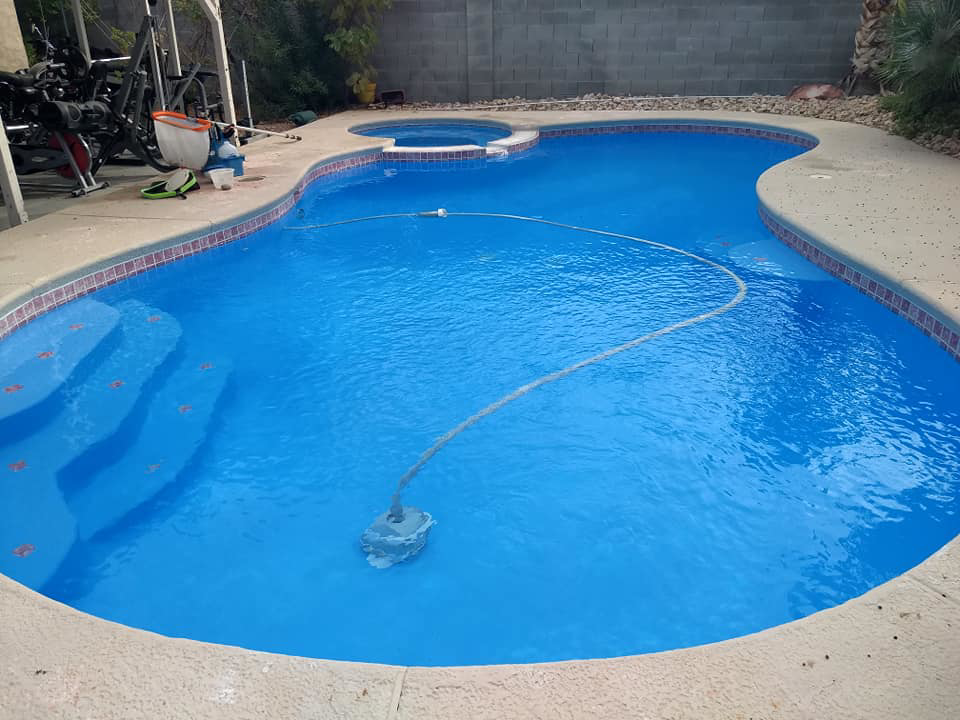 A robotic pool cleaner operating in a sparkling blue swimming pool by Bluemar Pool & Spa Services in North Las Vegas, NV.