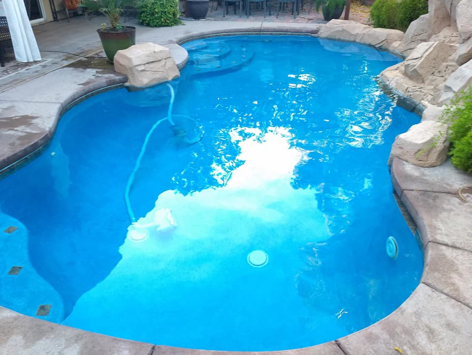 A robotic pool cleaner actively cleaning a residential swimming pool by Bluemar Pool & Spa Services in North Las Vegas, NV.