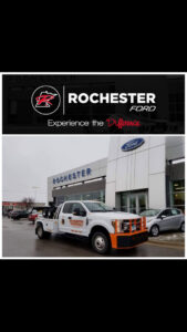 A white Rochester Towing truck parked in front of a Rochester Ford dealership in Rochester, MN.