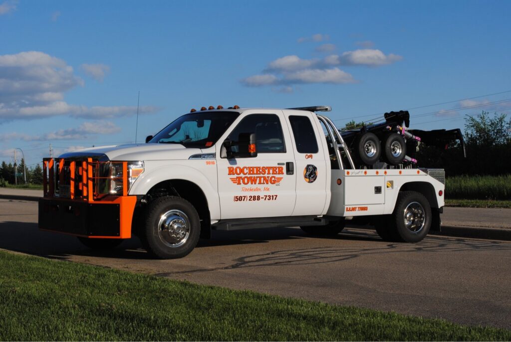 A white Rochester Towing truck with an orange bumper parked on the roadside in Rochester, MN.