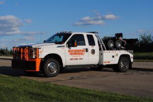 A white Rochester Towing truck with an orange bumper parked on the roadside in Rochester, MN.