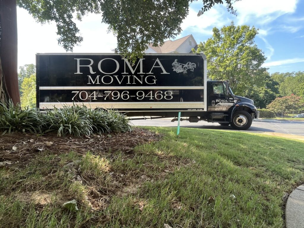 A Roma Moving truck parked in a leafy residential area in Charlotte, NC, ready for a move.