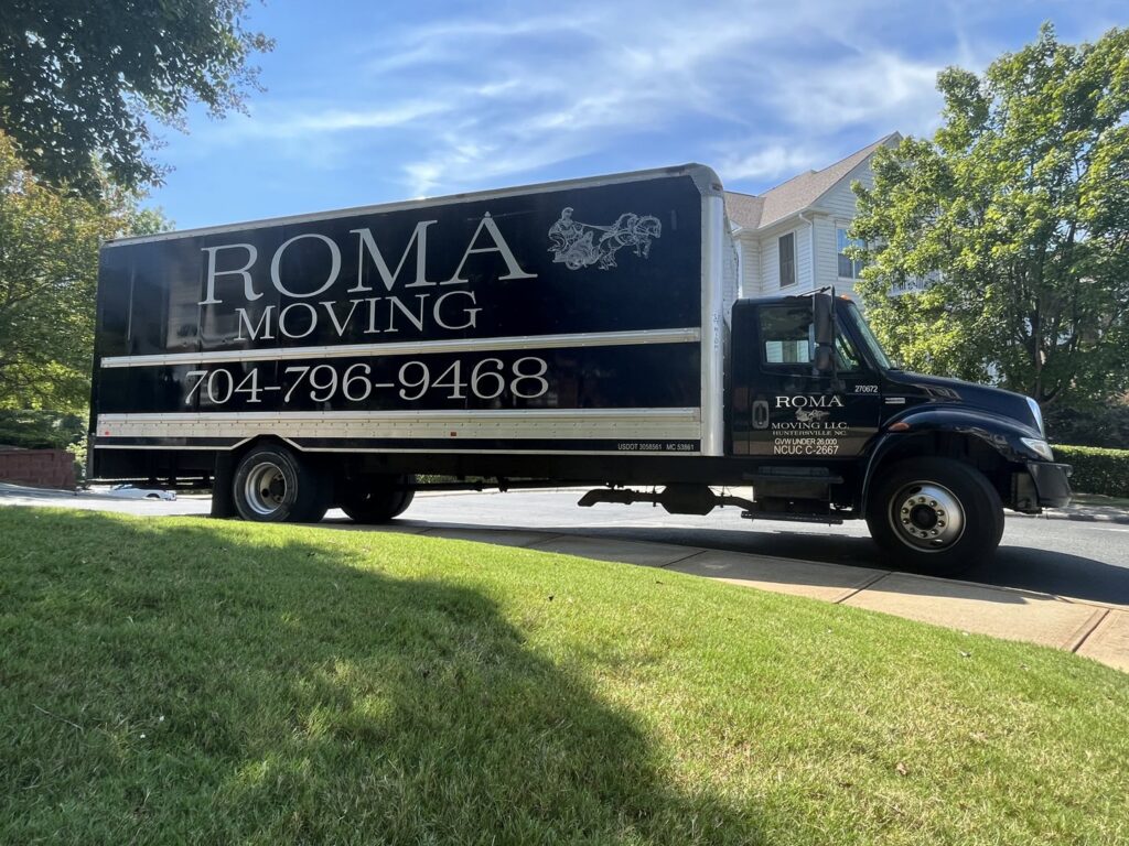 A Roma Moving truck parked on a sunny residential street in Charlotte, NC, prepared for a home relocation.