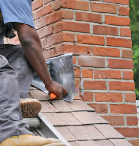 A skilled worker performing chimney flashing repair on a roof to prevent water damage for Abreu Home Improvements in Brockton, MA.
