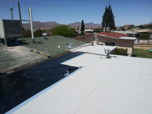 A roof repair in progress, showing new white coating and black underlayment for waterproofing by DryTech in El Paso, TX.