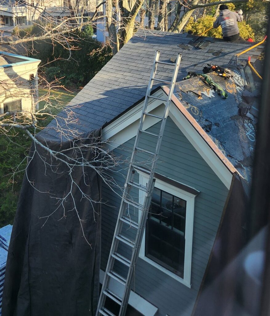 A residential roof covered in snow under a clear blue sky, ready for professional snow removal by Senco Home Services in Lynn, MA.