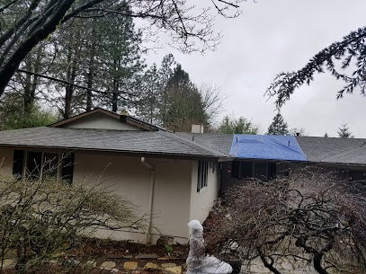 A house with a blue tarp on the roof, indicating storm or water damage repair by PacWest Restoration in Tigard, OR