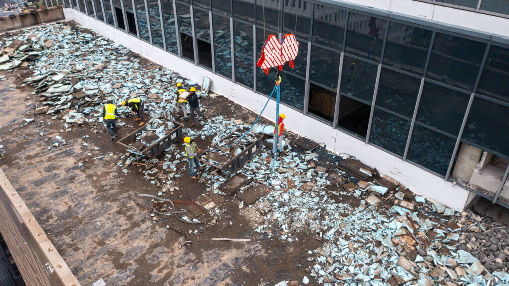 Aerial view of a rooftop demolition project with workers and a crane, managed by Nuckles Services in Birmingham, AL
