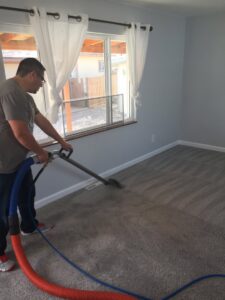 A cleaner meticulously cleaning the carpet in a bright room for Happy Client Cleaning Services in Fort Collins, CO.