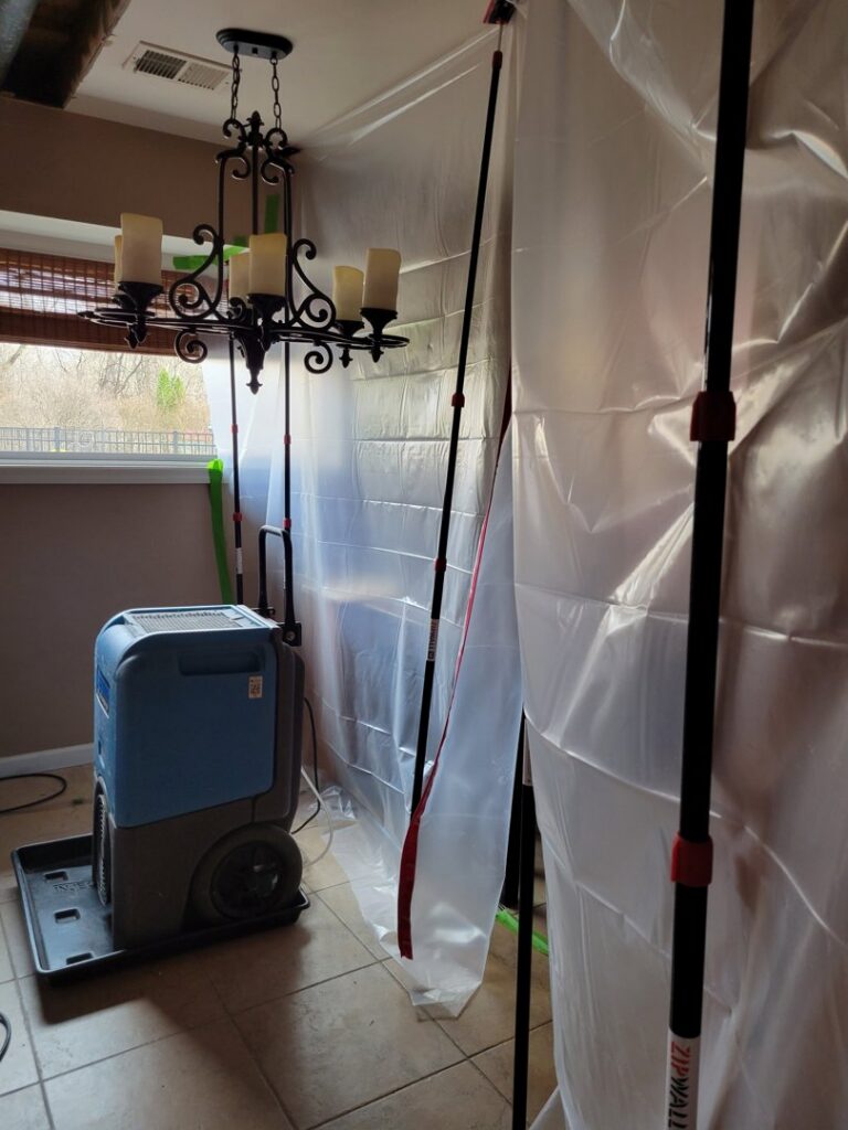 A room with a plastic containment barrier and a large dehumidifier for water damage restoration by New Method Restoration in Edison, NJ.