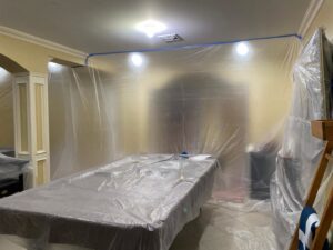 A room with furniture and walls covered in plastic for containment during water damage restoration by Mold Master Restoration in Jersey City, NJ