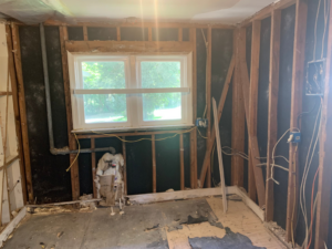 A room with walls stripped to studs, exposing wiring and pipes, during demolition by Clean Slate Demolition in Rock Hill, SC.