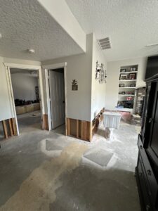 A room with exposed wall studs and water stains on the floor from water damage remediation by Restorex in Petaluma, CA.