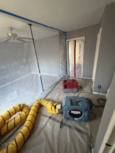 A room with plastic containment and drying equipment for water damage restoration by Mold Master Restoration in Jersey City, NJ