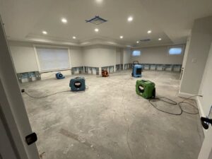 A large room with lower drywall removed and multiple drying machines for water damage restoration by Mold Master Restoration in Jersey City, NJ