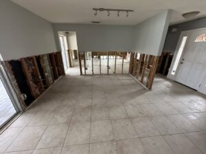 A room with lower drywall removed, exposing studs and concrete blocks for water damage remediation by Catalyst Restoration in Hagerstown, MD.